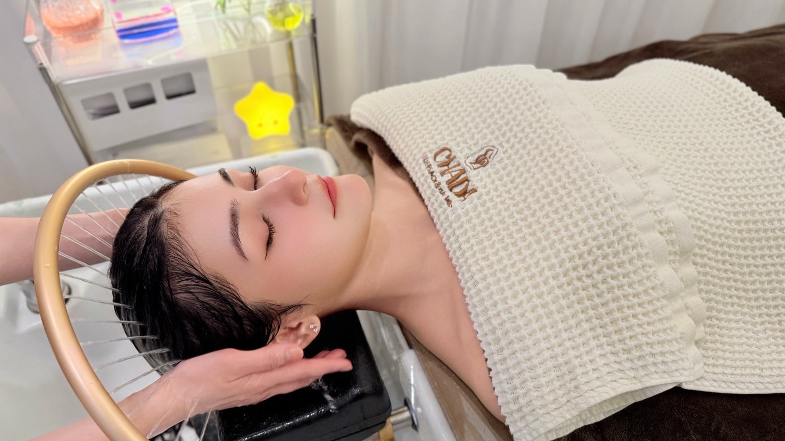 Guest enjoying a Vietnamese hair wash under the water arch at Chada Sleep Salon